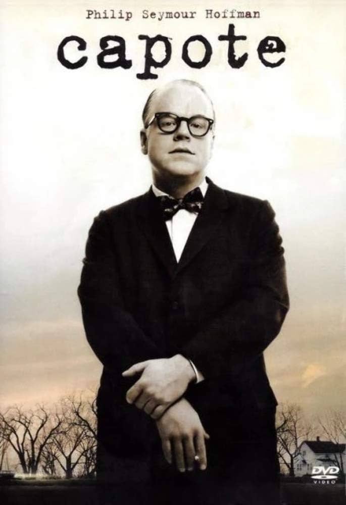 A man in a black suit, bow tie, and glasses 