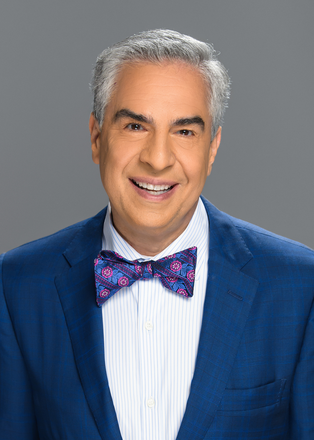 Photo of Paul Lisnek, a white man with grey hair who is wearing a blue suit with a bow tie.