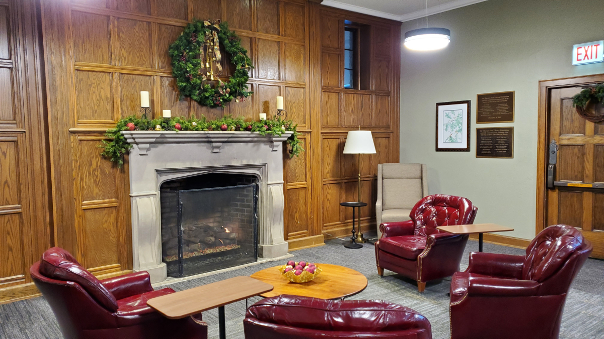 A photo of the Reading Room fireplace decorated with a wreath, candles, and boughs